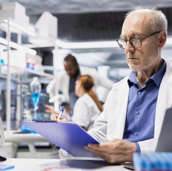 Elderly,Man,In,Laboratory,Writing,Observation,Notes,On,Clipboard,Document